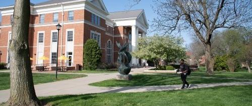 Student walking near Crounse Hall in springtime